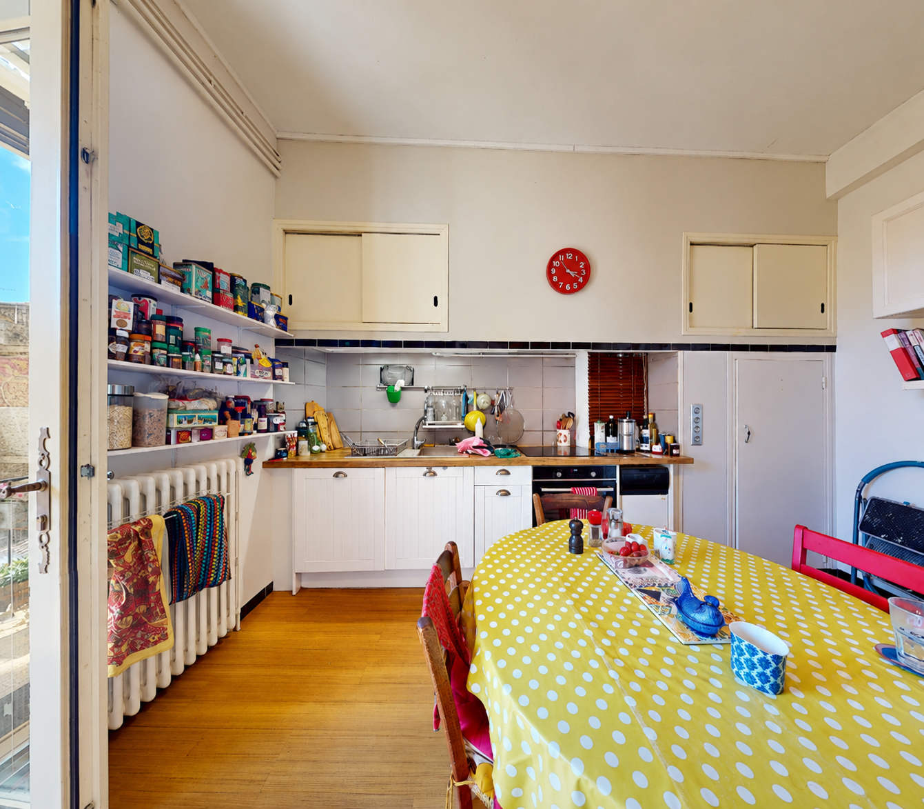 Ancienne cuisine à Béziers avant rénovation avec meubles blancs, placard intégrés et radiateur