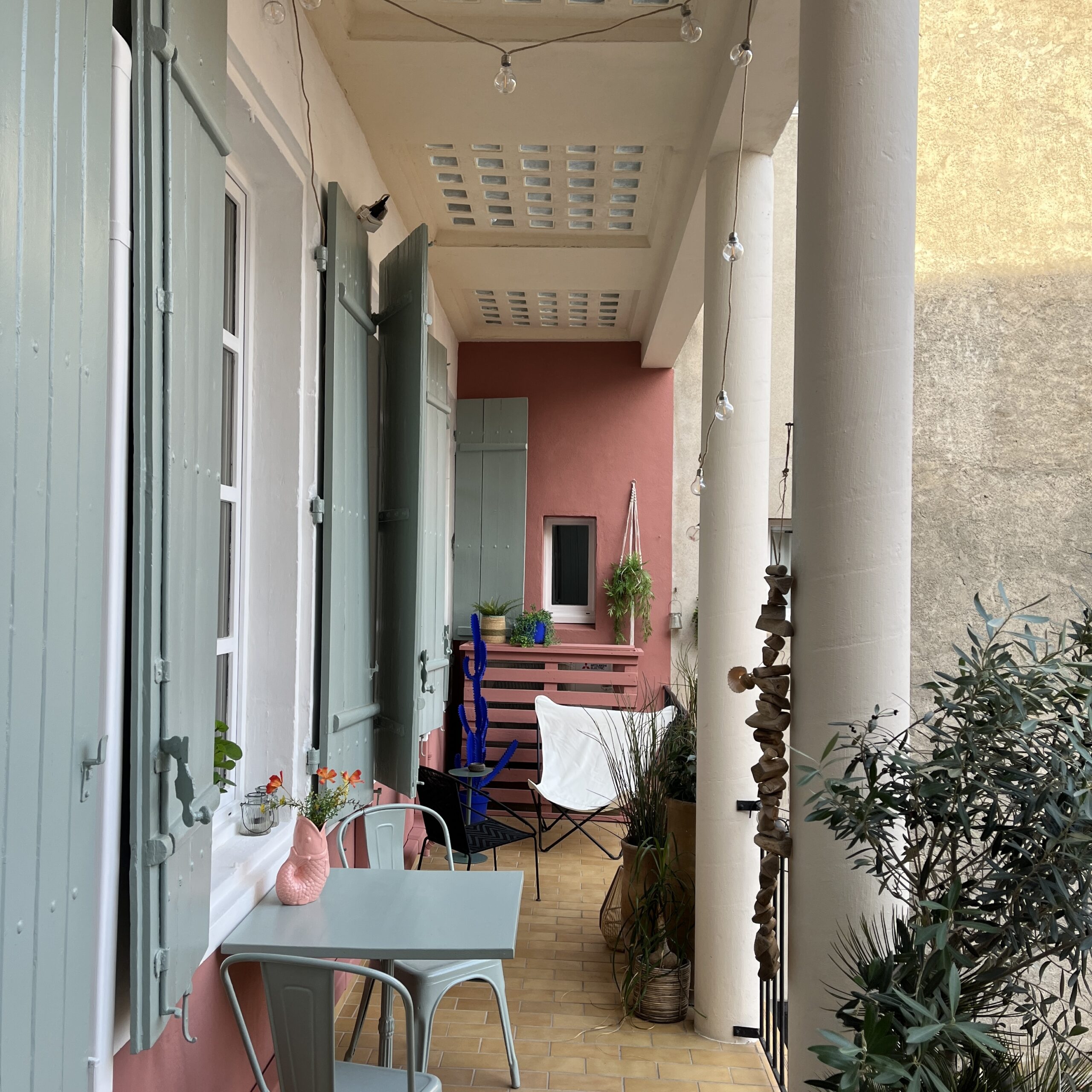 Terrasse aménagée après réalisation avec volets verts mobilier et plantes